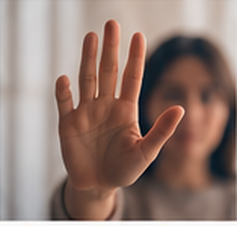 Mano extendida en señal de alto frente a una persona desenfocada